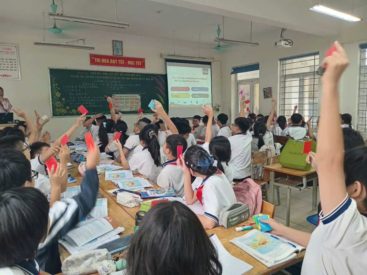 A group of students raising their hands in a classroom
Description automatically generated